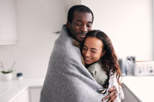couple cuddling while wrapped in a blanket