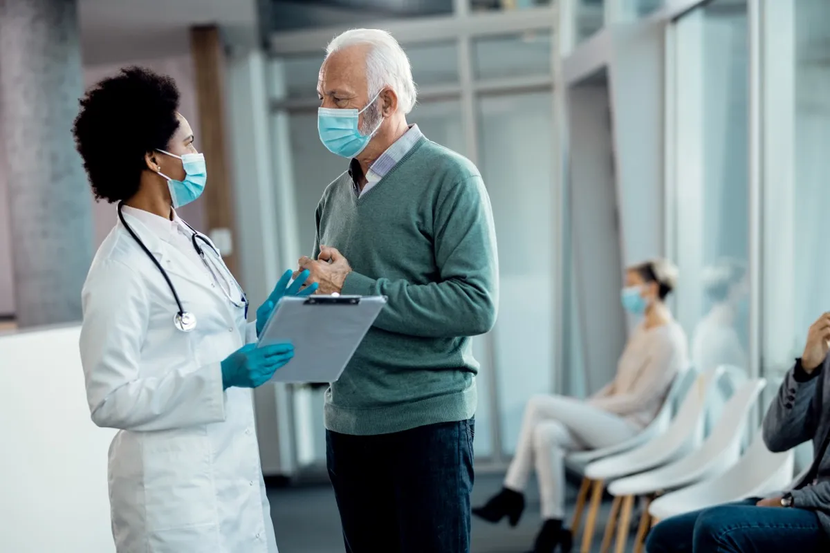 doctor wearing a mask speaking to patient