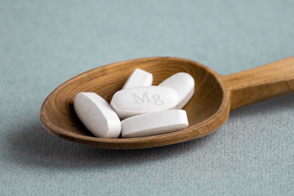 magnesium supplements in wooden spoon