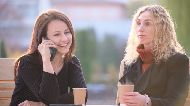 woman ignoring friend while she talks on the phone