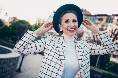 Smiling stylish senior woman in plaid jacket and black hat