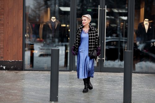 Stylish senior woman wearing blue dress and plaid wool flannel jacket with boots