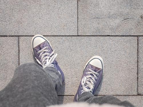 Top view of feet turned out wearing purple Converse sneakers