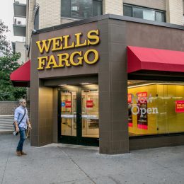 The exterior of a Wells Fargo branch with people walking by