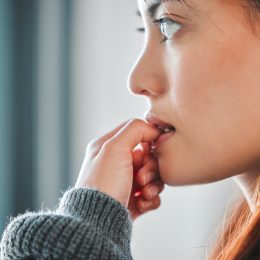 Close up of a woman biting her nails and looking anxious