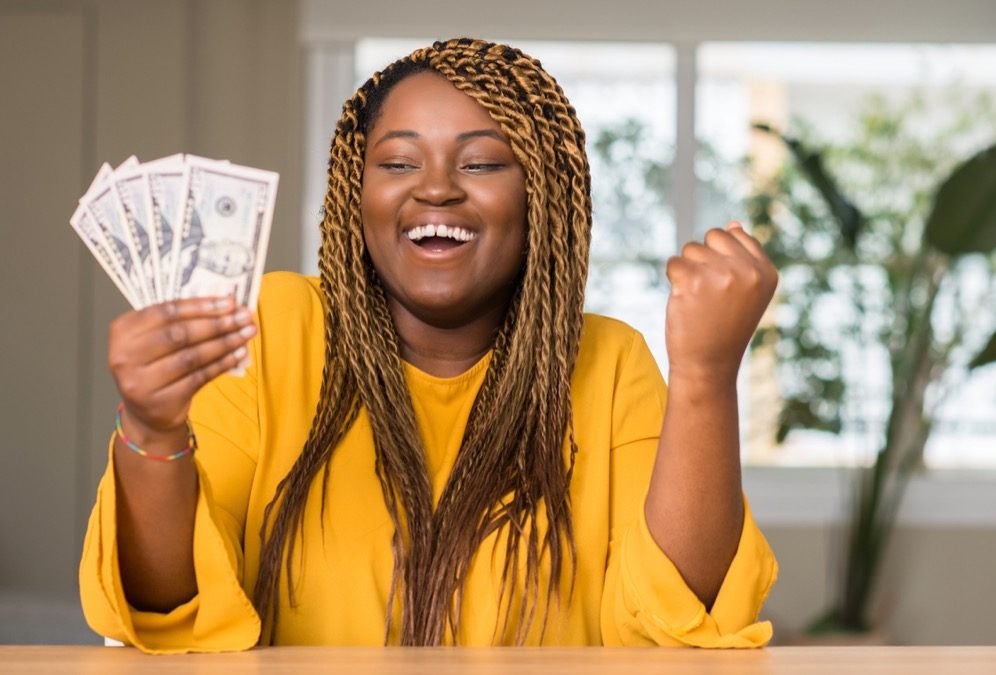 A woman holding cash and smiling