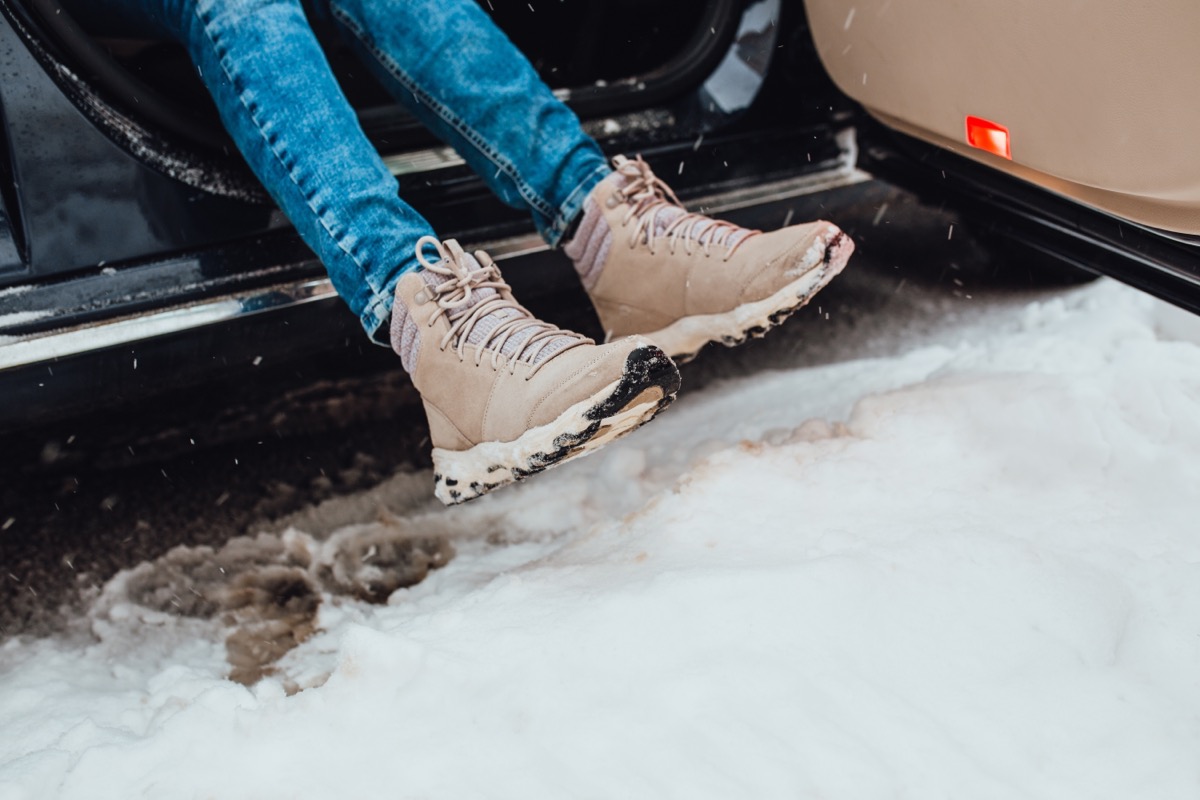 The girl kicks the snow off her boots while getting into the car - careful and economical use of a taxi - maintaining the cleanliness and presentation of a taxi