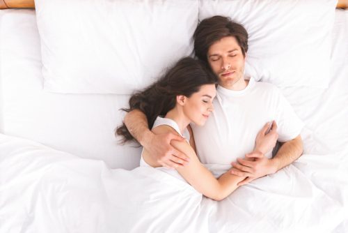 man and woman sleeping and cuddling in bed