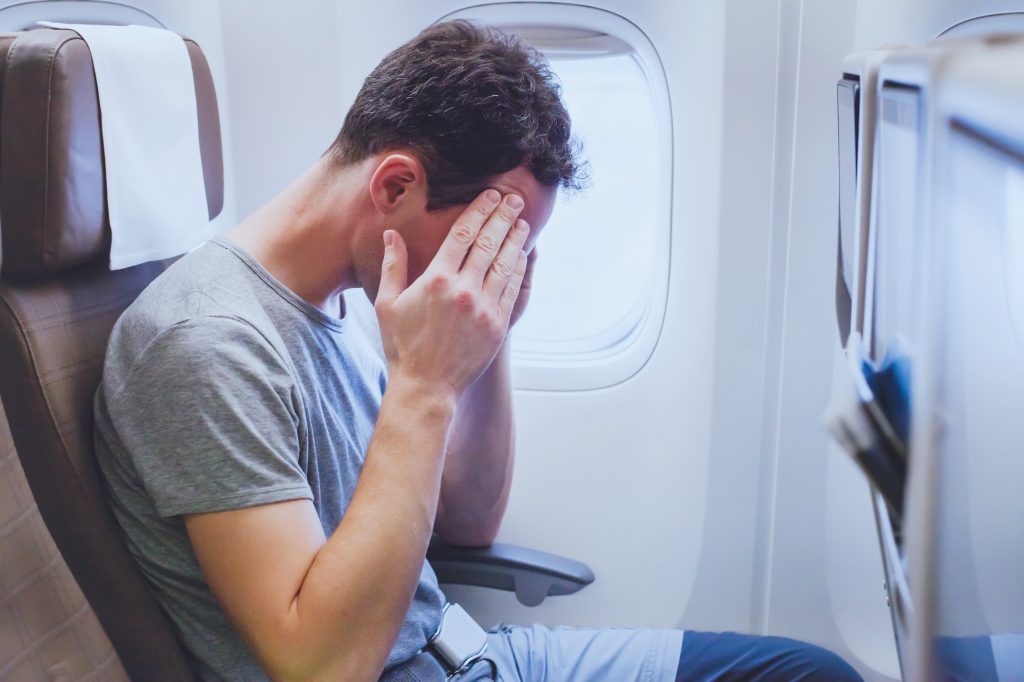 Man sitting in airplane seat with his head in his hands
