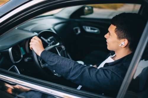 man in wireless headphones driving car