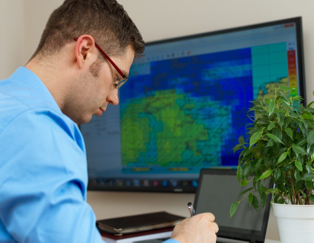 Male meteorologist working on laptop.