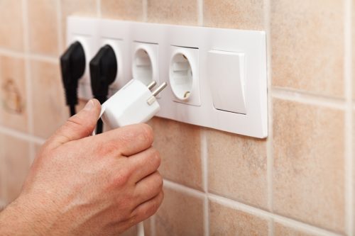 Person Unplugging Cords from Outlet