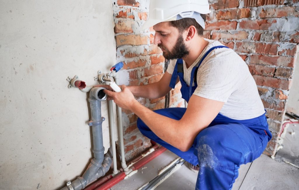 Male plumber working on pipes