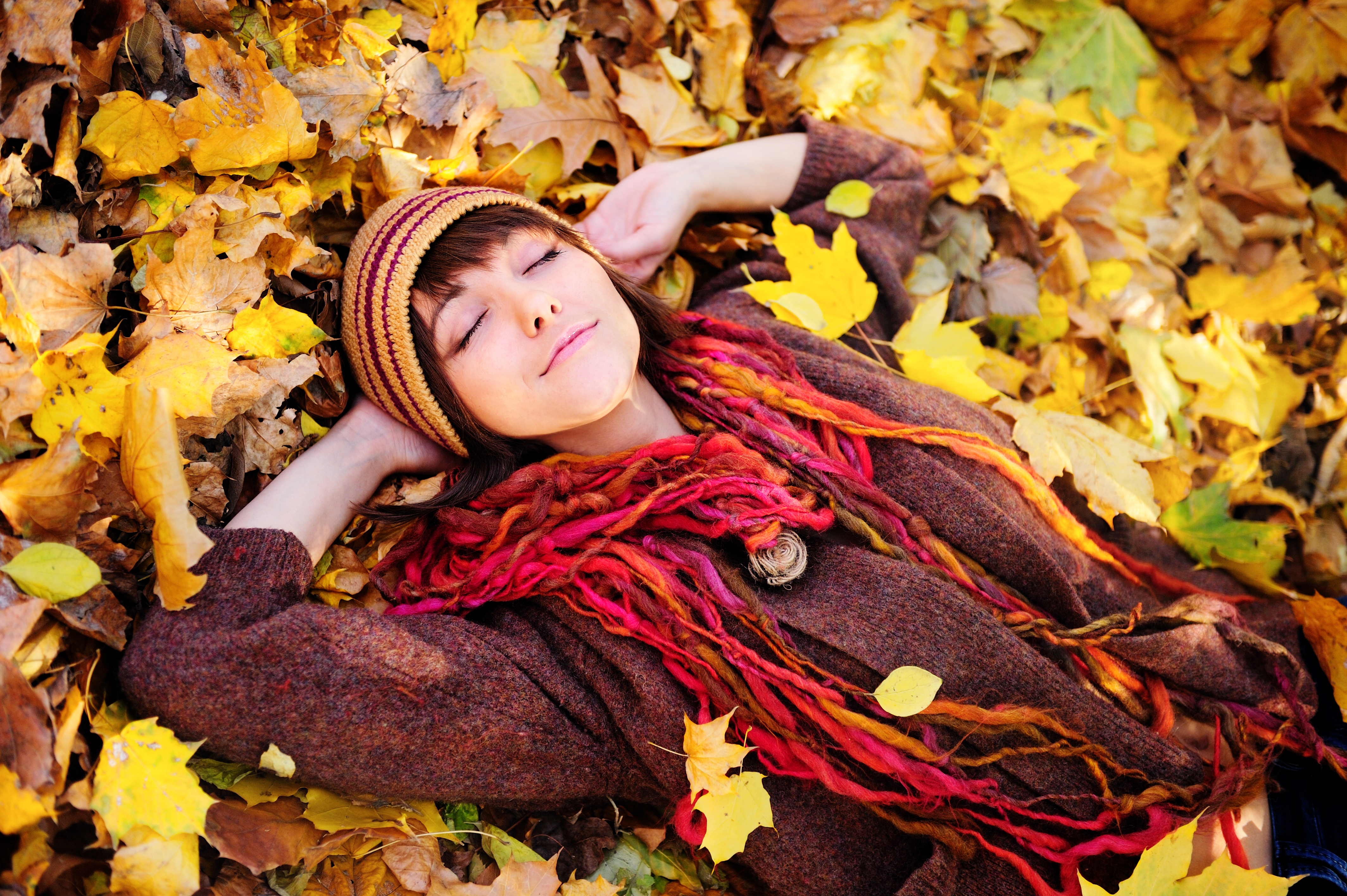 Happy girl resting in autumn leaves