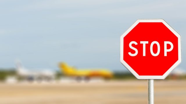 Red Stop sign on blured Airplane of Airliners are parking in International Airport.