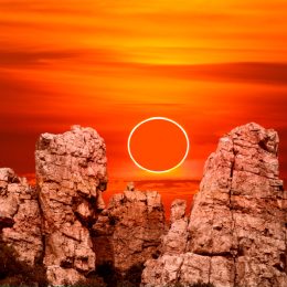 An annular solar eclipse rising over rock cliffs