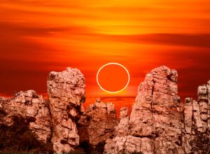 An annular solar eclipse rising over rock cliffs