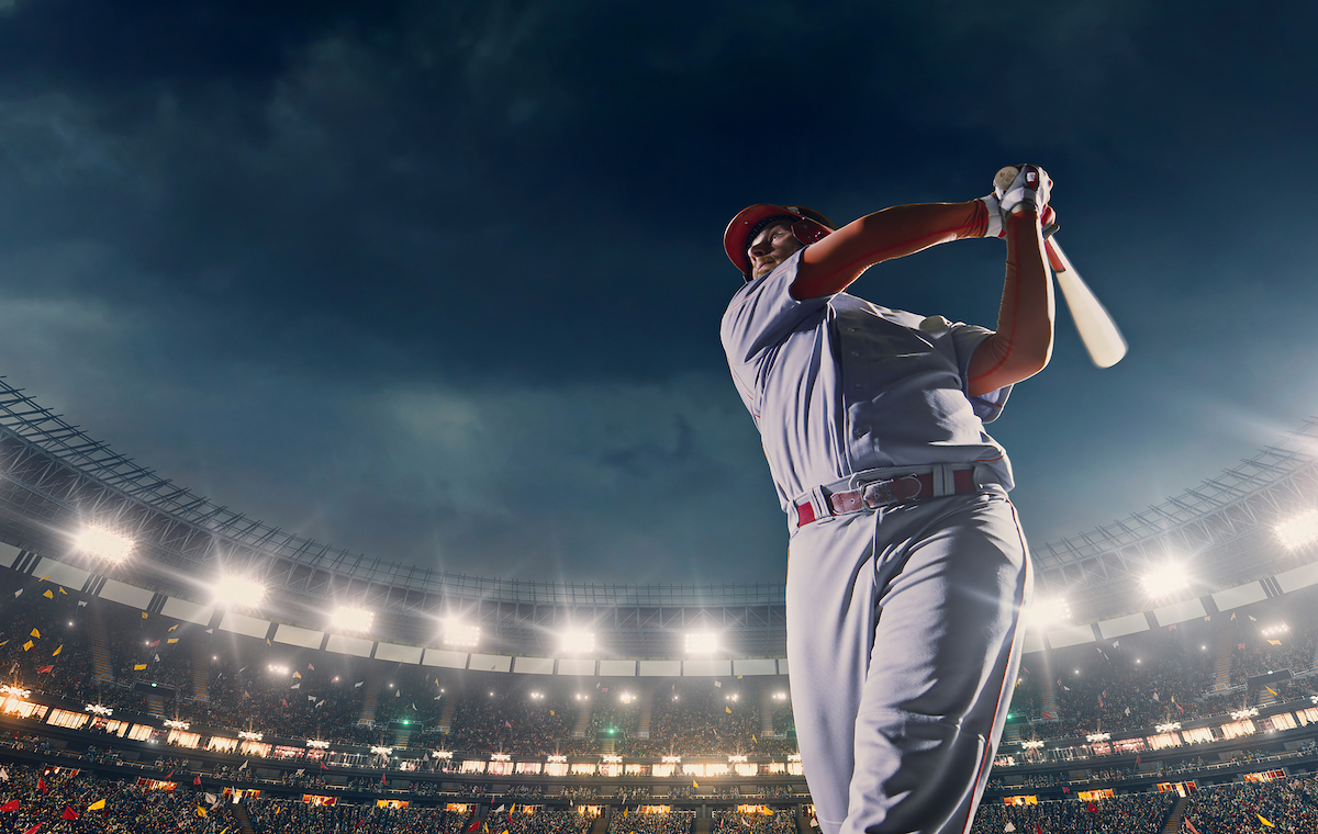 Baseball batter hitting ball during game on the professional stadium full of people.