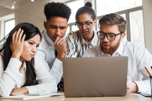 group of coworkers looking quizzically at something on a laptop