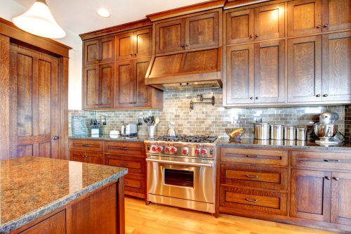 A kitchen with dark pine wood cabinets and dark granite counters