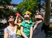 A family with young children watching a solar eclipse while wearing protective glasses