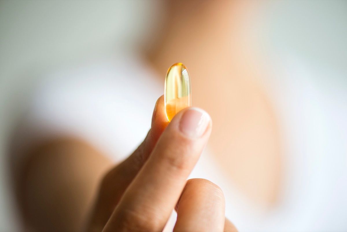 Woman holding omega 3 capsule.