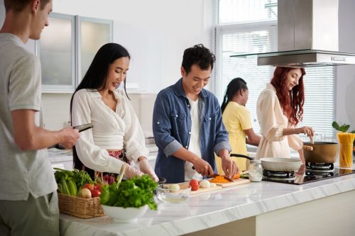 Group of friends cooking dinner together at kitchen counter