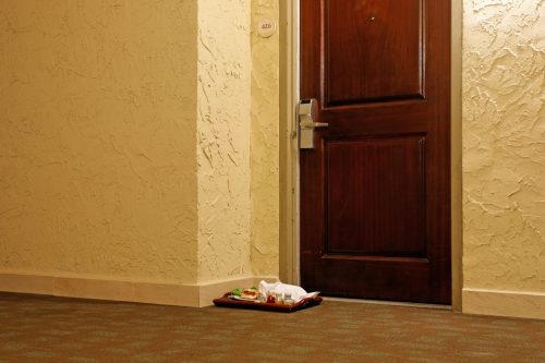 A half-eaten hamburger on a room service tray sits in the hallway of a hotel.