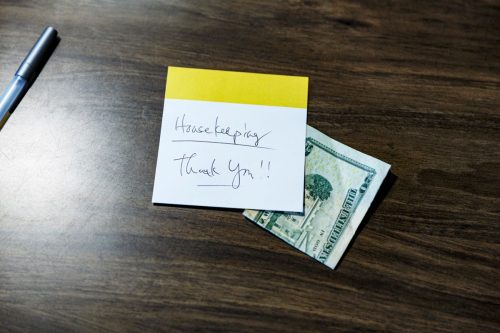 Handwritten "Thank You" note left in hotel room on wood desk top with a twenty dollar bill as a gratuity for the housekeeping staff.