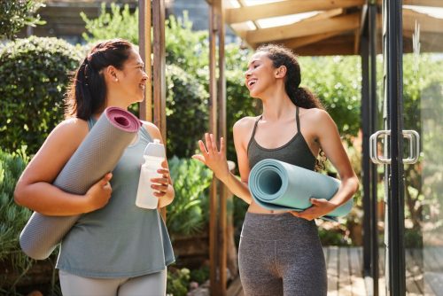 Fitness, yoga class and woman talking with training gear for sports, meditation and happy teamwork at wellness center. Pilates, workout and healthy people or friends with holistic exercise in nature