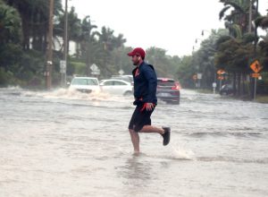 Storm Nicole nears hurricane strength as a man jogs through flooded roads in the Palm Beach area.