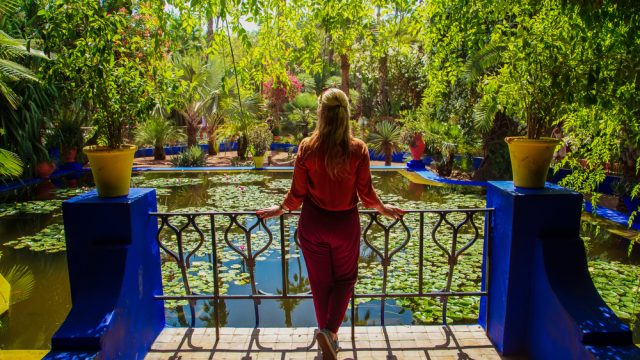A woman standing in front of a pond at the Jardin Majorelle