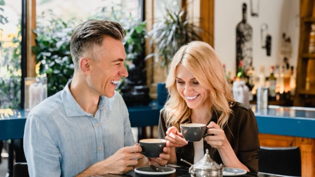 Happy cheerful caucasian middle-aged couple spouses drinking coffee talking enjoying romantic date together in cafe restaurant bar