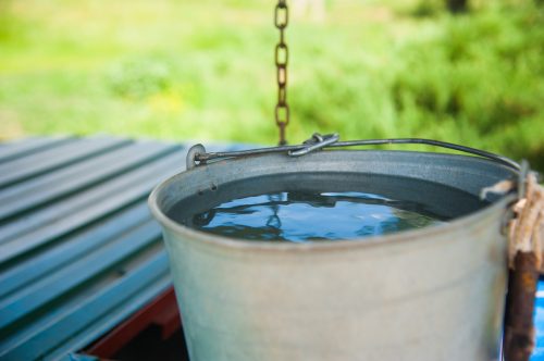 Close up of a metal bucket filled with water outside