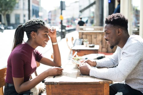 man and woman sitting at a table outside on a first date