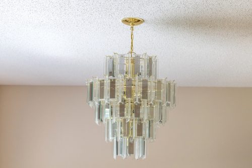 An old-fashioned retro hanging glass chandelier hanging from a popcorn ceiling.