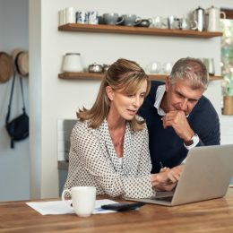 A senior couple planning their finance and paying bills while using a laptop at home.