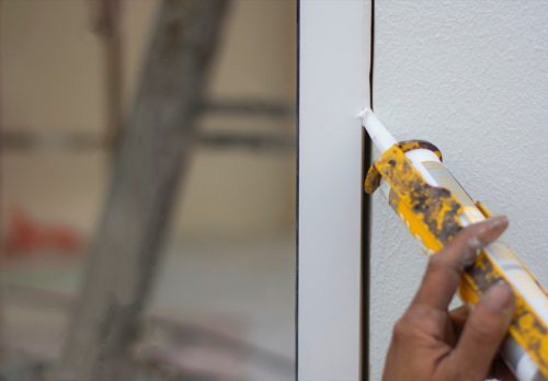 Repairman's hand installing the windows with gun silicone. closeup