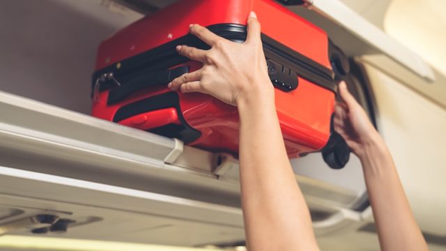 putting carry-on bag in overhead compartment