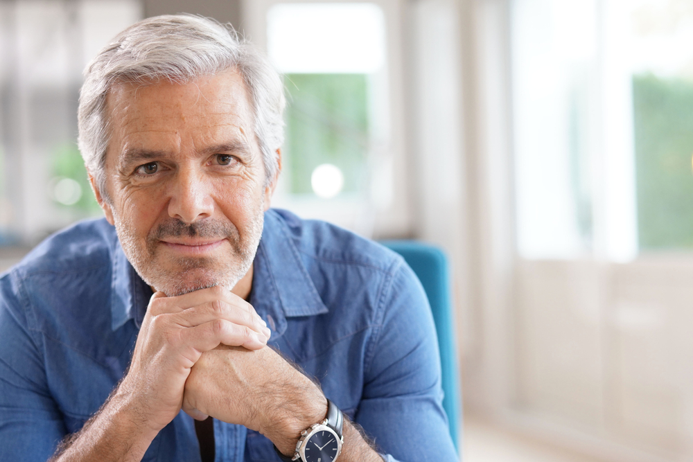 Handsome senior man at home with gray hair and blue button down shirt