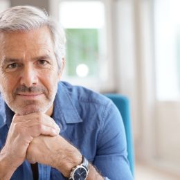 Handsome senior man at home with gray hair and blue button down shirt