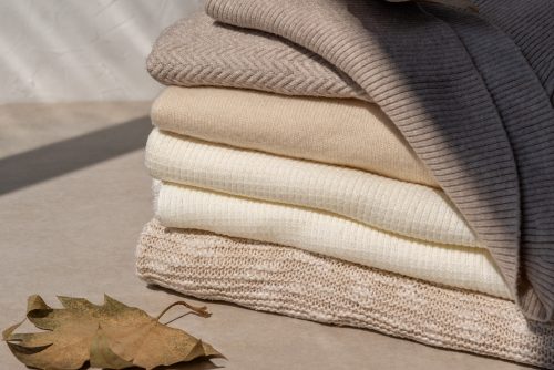 Stack of taupe and beige neutral sweaters for fall style concept
