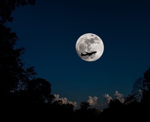 airplane flying during the full moon