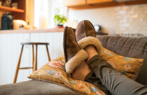Close-up of a woman's feet in cosy slippers as she relaxes on the sofa at home.