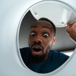 Looking up at a surprised man peering into his toilet bowl