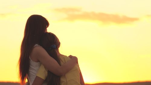 mother embracing daughter against the sunset