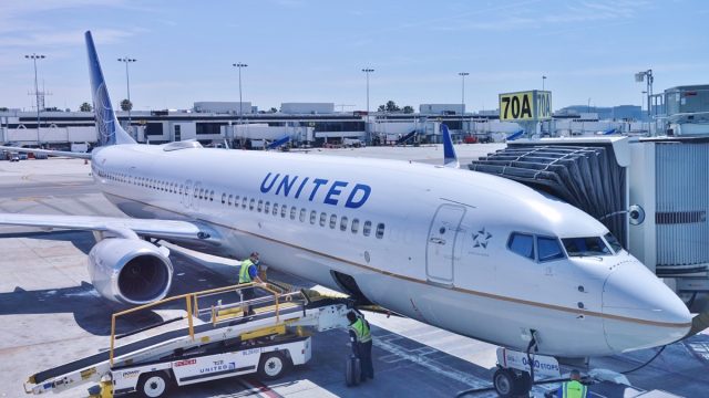 LOS ANGELES, CA -26 APR 2020- An airplane from United Airlines (UA) and a baggage handler wearing a face mask during the COVID-19 crisis at the Los Angeles International Airport (LAX).
