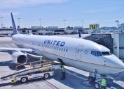 LOS ANGELES, CA -26 APR 2020- An airplane from United Airlines (UA) and a baggage handler wearing a face mask during the COVID-19 crisis at the Los Angeles International Airport (LAX).