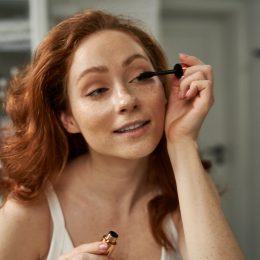 Redhead woman using mascara in the domestic bathroom