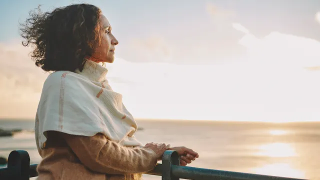 Mature woman watching the sunset over the ocean